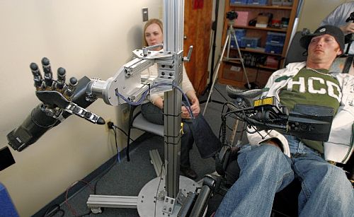 Assistant professor Jennifer Collinger, left, watches as quadriplegic research subject Tim Hemmes operates the mechanical prosthetic arm in a testing session at UPMC.