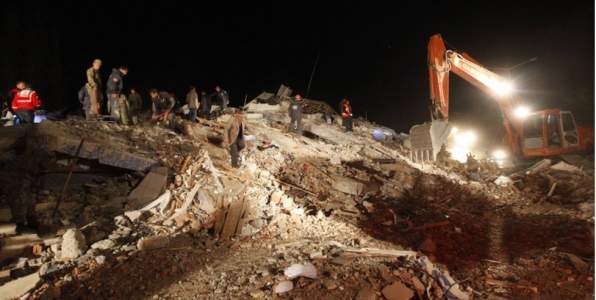 nighttime, track hoe on top of rubble from earthquake