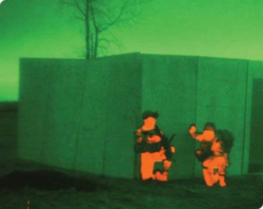 Night vision and thermal of two soldiers positioned behind a wall